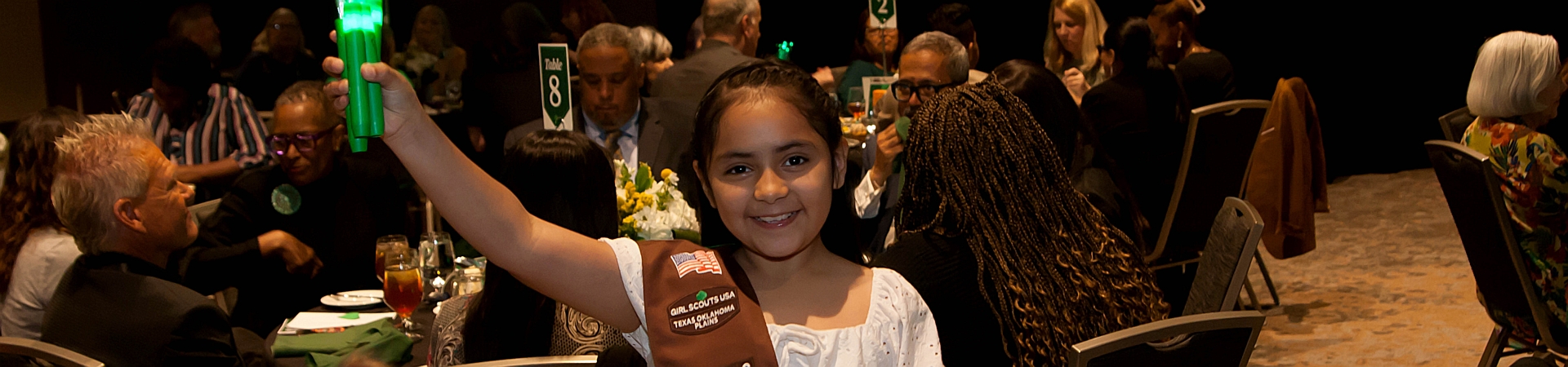  cadette girl scout hosting a table and smiling at a civics event with other middle school and high school girls  